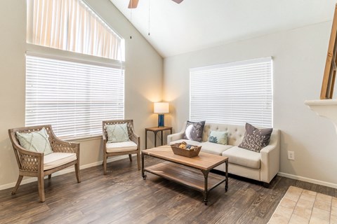 a living room with a couch and chairs and two windows